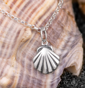 Sterling silver clamshell necklace laying on a seashell