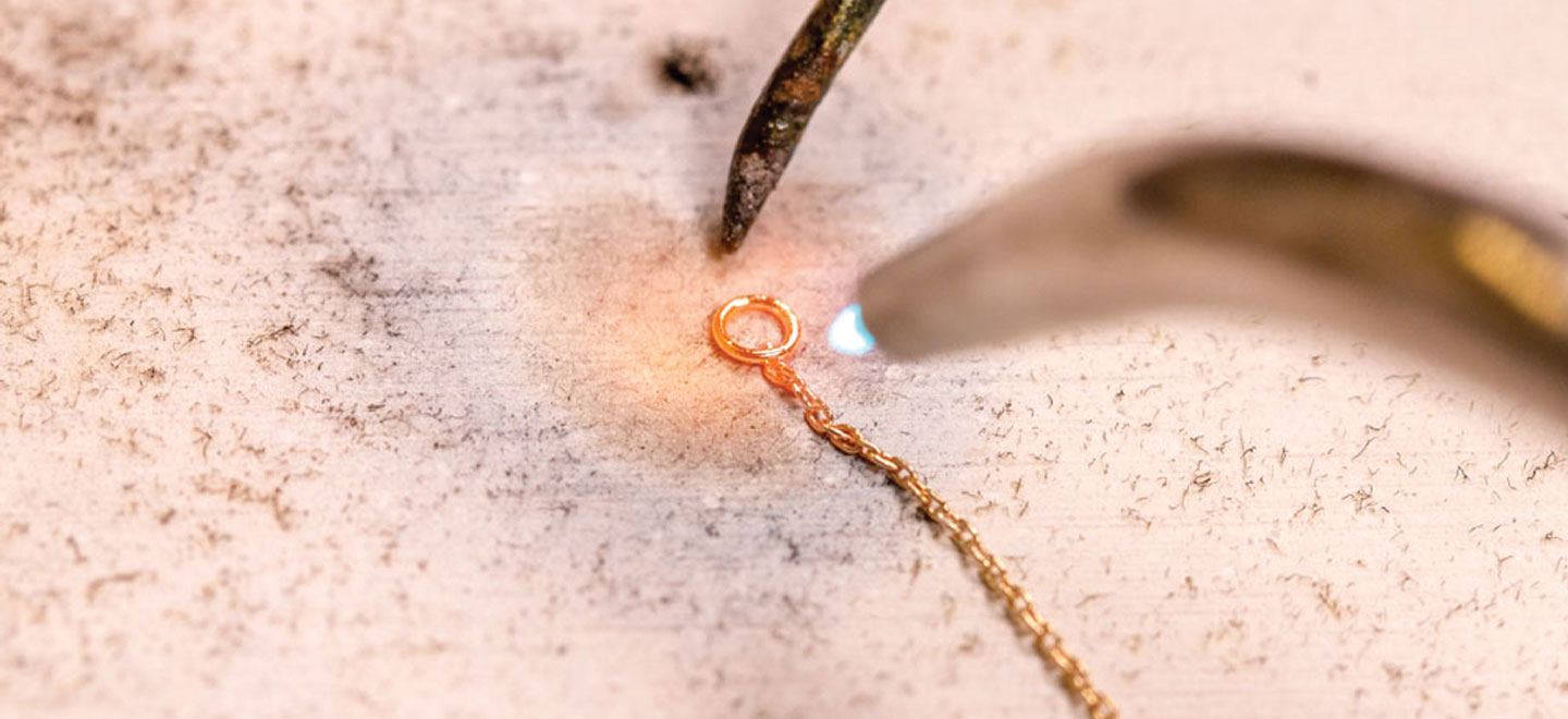 Tip of jewelry torch soldering a jump ring to a chain