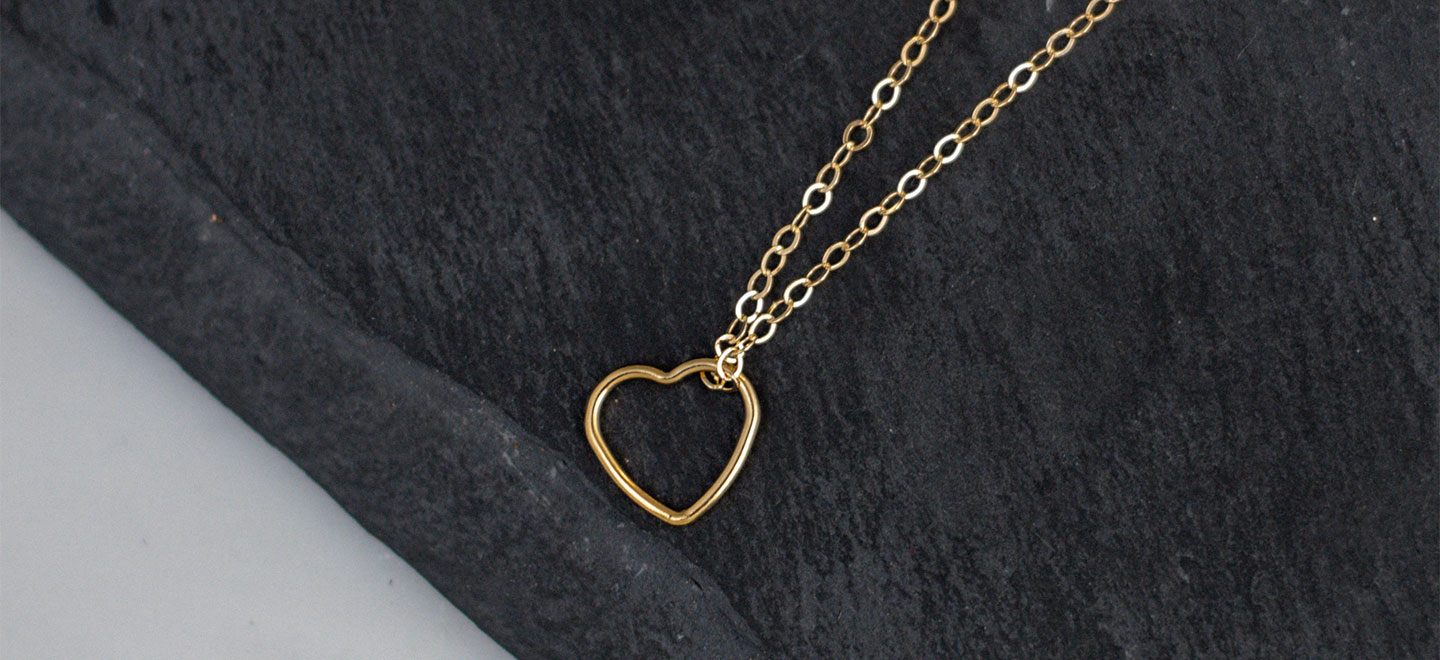 Gold-filled heart necklace laying on black table top