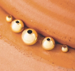 Round gold-filled beads sitting on a terracotta pot