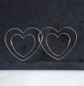 Sterling silver hoop earrings shaped like hearts on a piece of slate