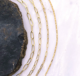 Four styles of gold-filled jewelry chain laying on marble tabletop