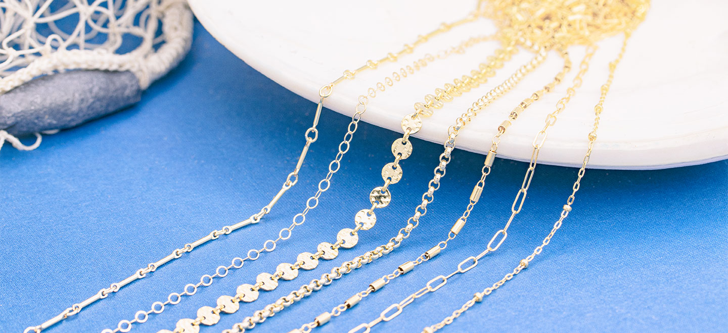 Different styles of gold jewelry chain laying on seashell