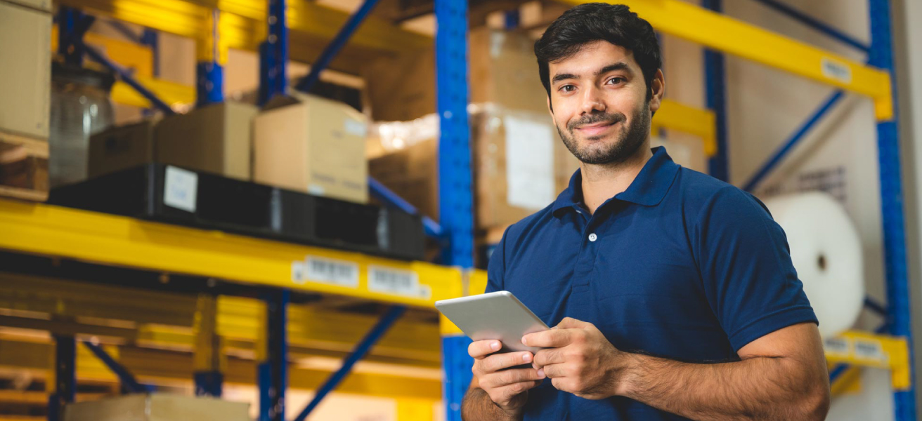 Smiling man standing with tablet in warehouse