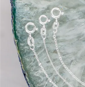 Three sterling silver chains with spring rings displayed on a light blue geode slice