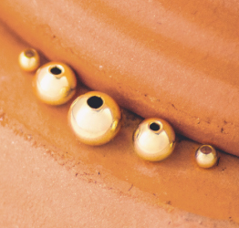 Round gold-filled beads sitting on a terracotta pot