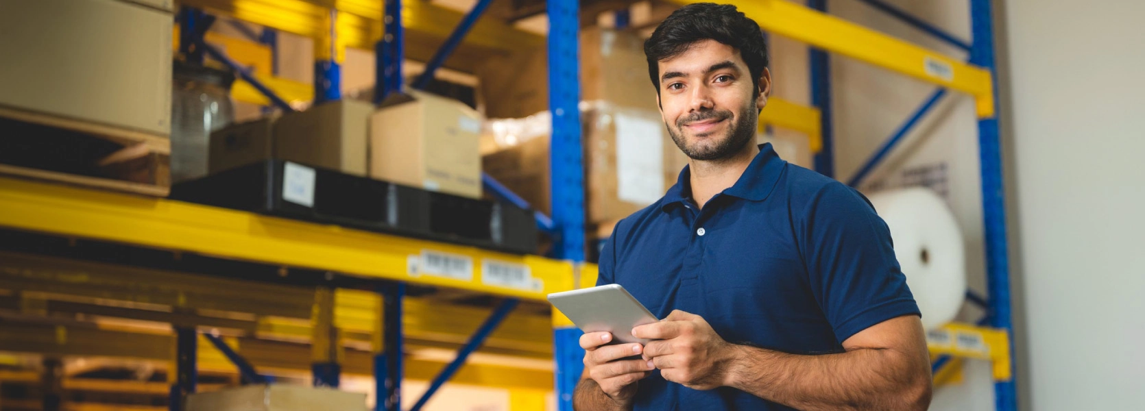 Smiling man standing with tablet in warehouse